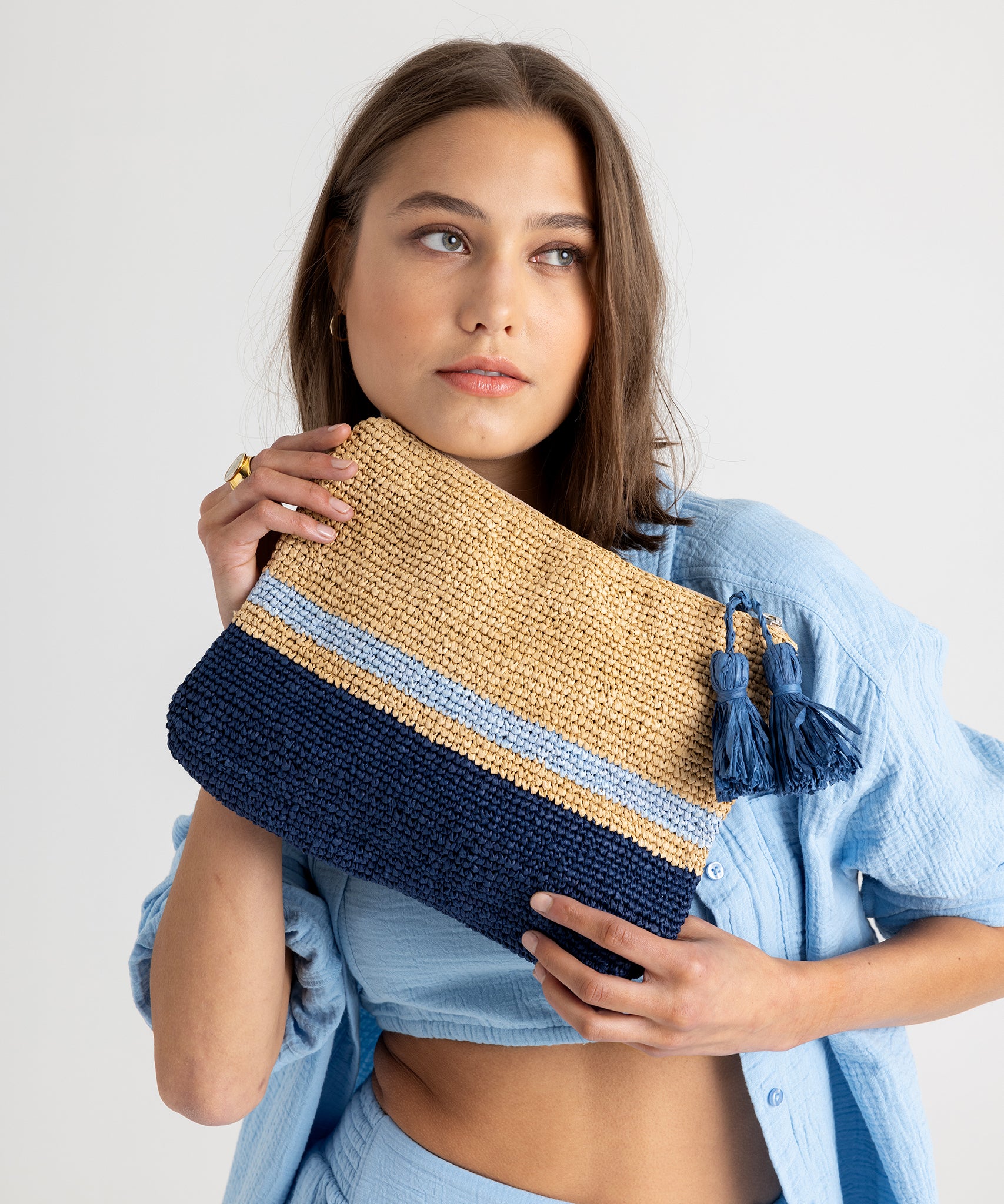 Tropic Stripe Clutch in color Natural/Navy held by model