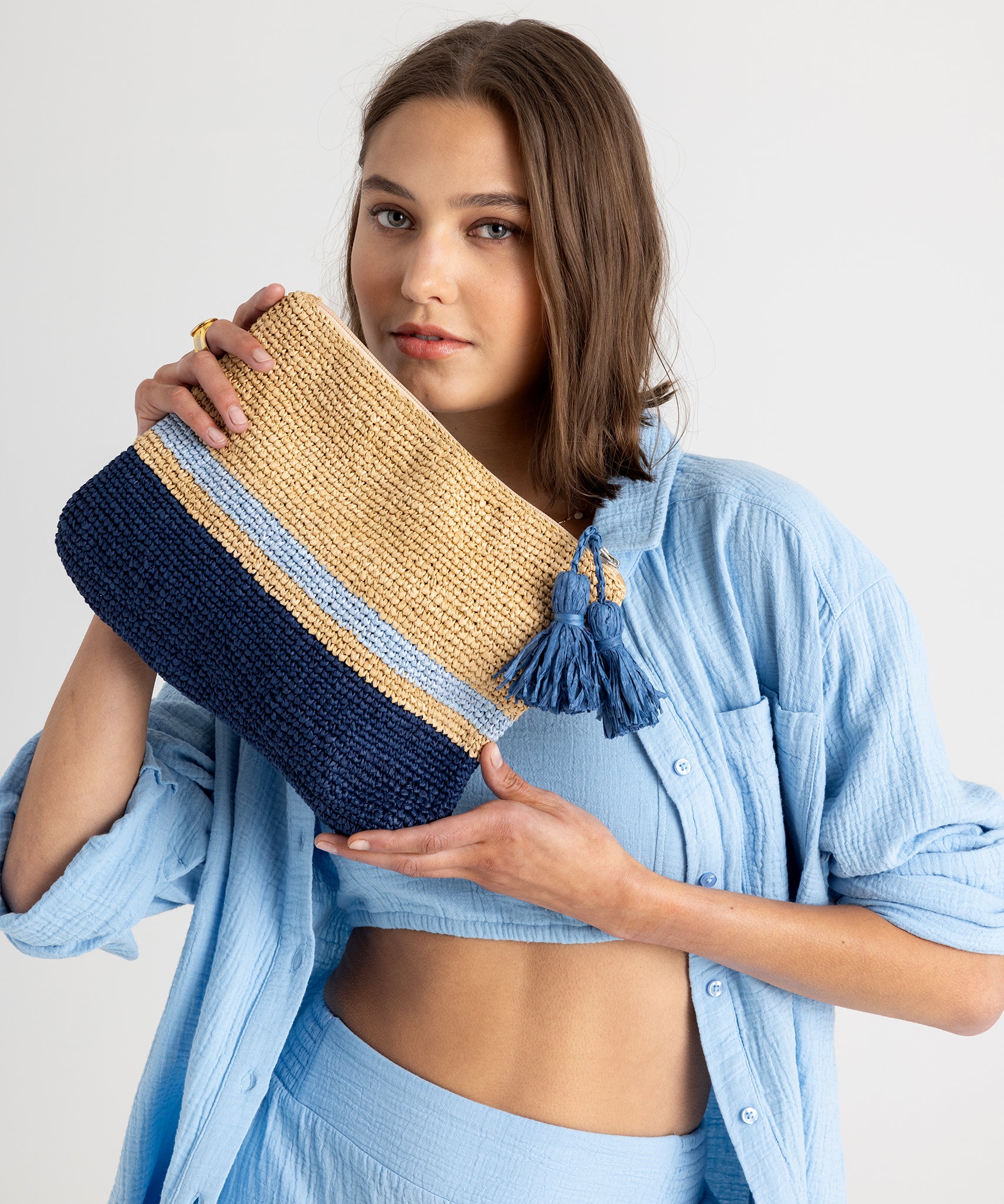 Tropic Stripe Clutch in color Natural/Navy held by model