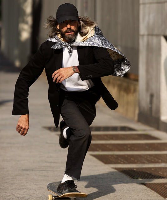 A portrait of Matteo Maresi wearing his echo 100 scarf and riding a skateboard