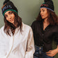 Two models in horoscope beanies. One is Taurus and one is Scorpio.