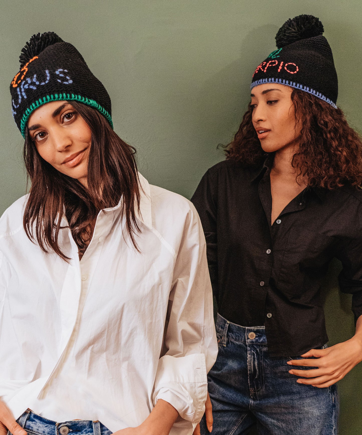 Two models in horoscope beanies. One is Taurus and one is Scorpio.