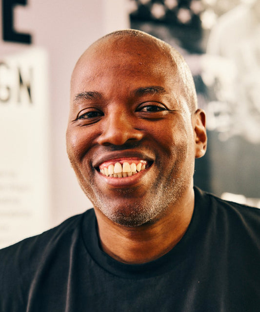 A potrait image of Cey Adams smiling in a black t-shirt.
